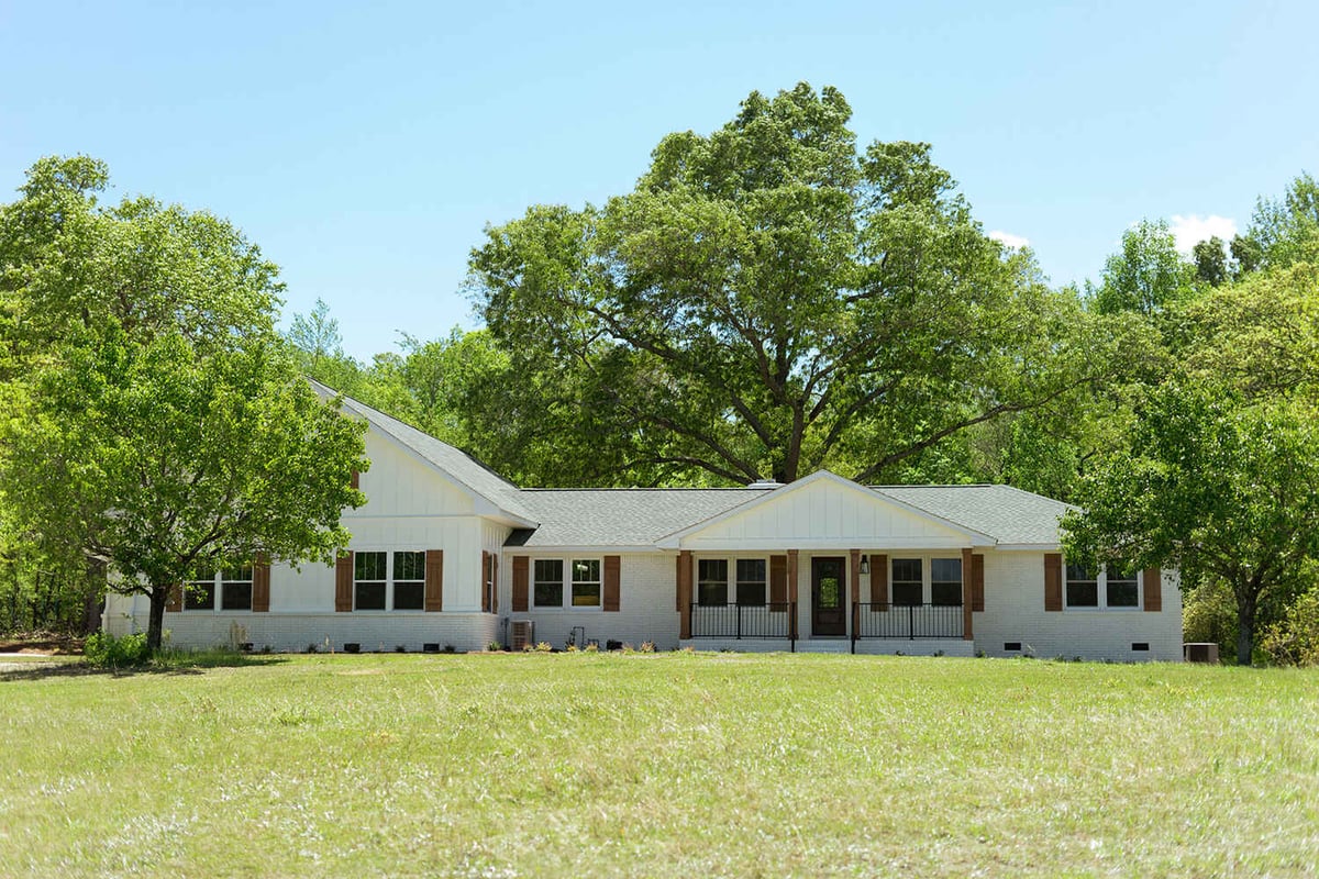 Exterior of home with white siding and wood window shutters
